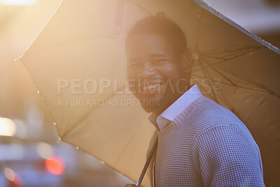 Buy stock photo Portrait of a young man holding an umbrella on a rainy day in the city