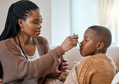 Buy stock photo Shot of a young mother giving her sick son cough syrup at home