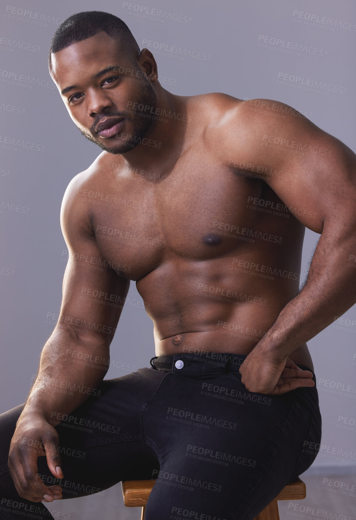 Buy stock photo Studio shot of a handsome and muscular young man posing against a grey background