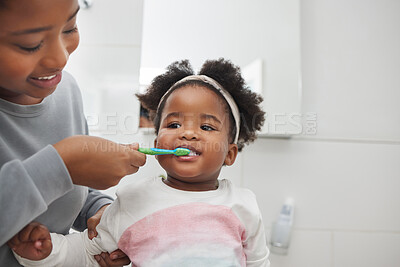 Buy stock photo Shot of a mother brushing her little daughter's teeth in the bathroom at home