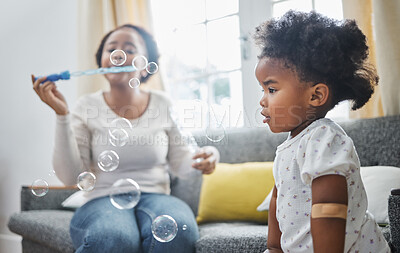 Buy stock photo Shot of a young mother and daughter having fun with bubbles at home