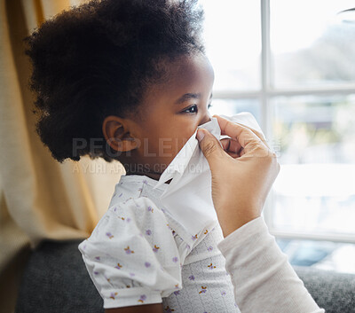Buy stock photo Shot of a little girl blowing her nose into a tissue at home