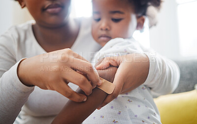 Buy stock photo Shot of a mother applying a plaster to her daughter's arm at home