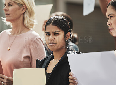 Buy stock photo Cropped portrait of an attractive young woman holding a sign while taking part in a political rally