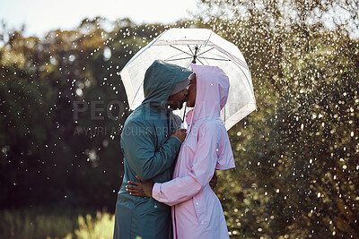 Buy stock photo Shot of an affectionate couple standing under an umbrella while out in the rain