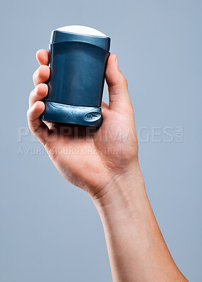 Buy stock photo Shot of an unrecognizable man holding deodorant against a blue background