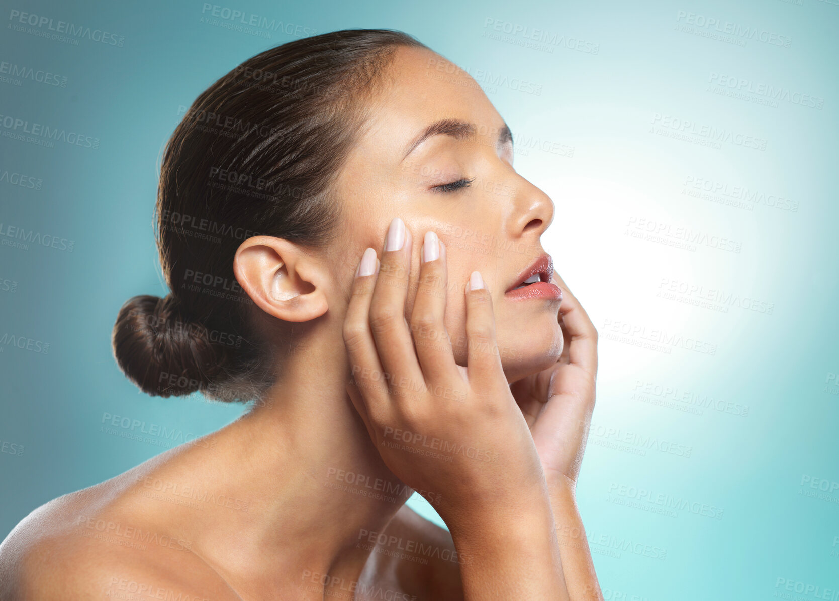 Buy stock photo Shot of a young female touching a her soft skin against a blue background