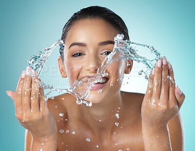 Buy stock photo Shot of a young female washing her face against a blue background