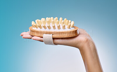 Buy stock photo Cropped shot of an unrecognisable woman holding a body brush against a blue background in the studio