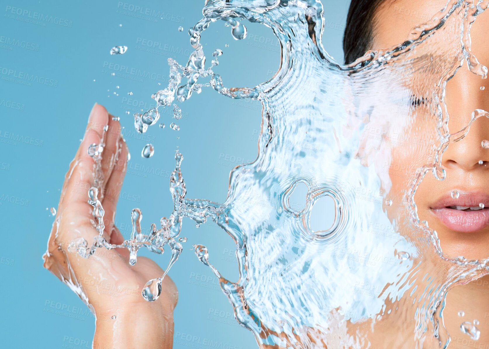 Buy stock photo Cropped shot of an unrecognisable woman posing against a blue background in the studio and splashing her face with water