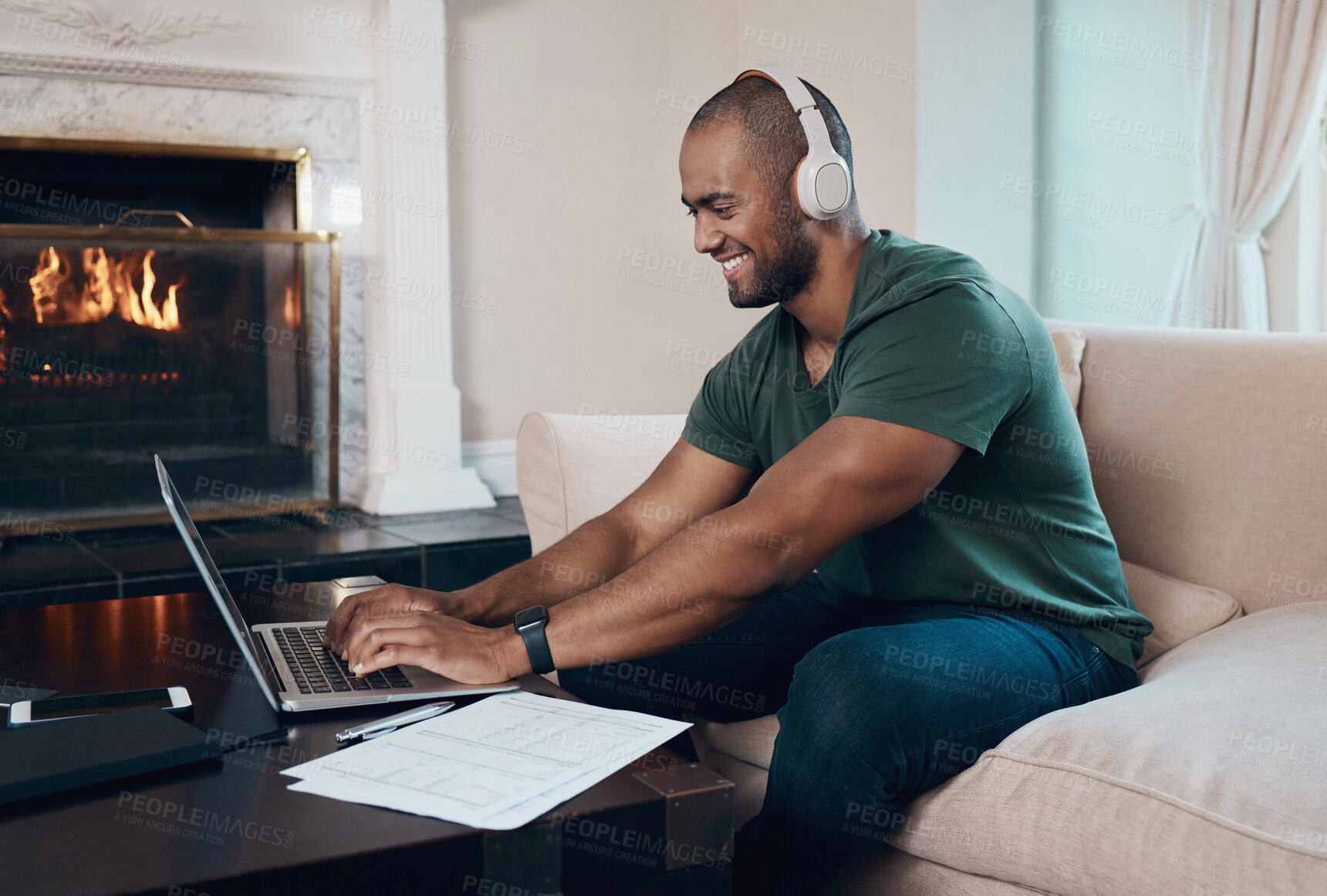 Buy stock photo Shot of a young businessman working on his laptop while listening to music