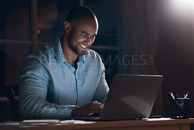 Buy stock photo Shot of a young businessman using his laptop while working late at night