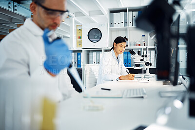 Buy stock photo Shot of a young scientist writing notes while conducting medical research in a laboratory