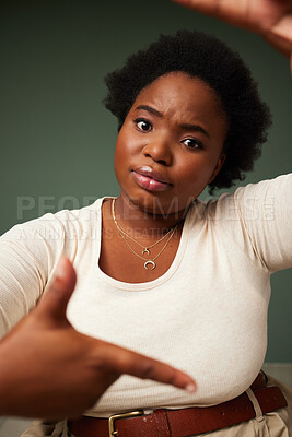 Buy stock photo Hand, frame and black woman portrait in studio with sign for photo, photography or fun picture on green background. Face, lady and beauty influencer with emoji finger for social media or selfie