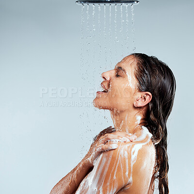 Buy stock photo Shot of a young woman taking a shower against a grey background