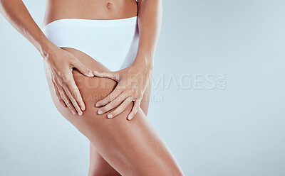 Buy stock photo Studio shot of an unrecognizable young woman squeezing her thigh against a grey background