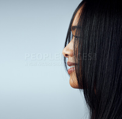 Buy stock photo Side shot of a beautiful young woman posing against a blue background