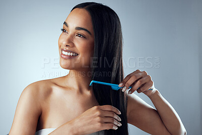Buy stock photo Studio shot of an attractive young woman combing her hair against a grey background