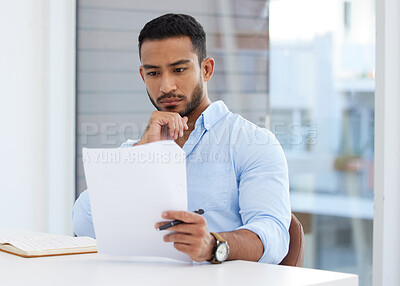 Buy stock photo Shot of a young businessman going through paperwork in an office