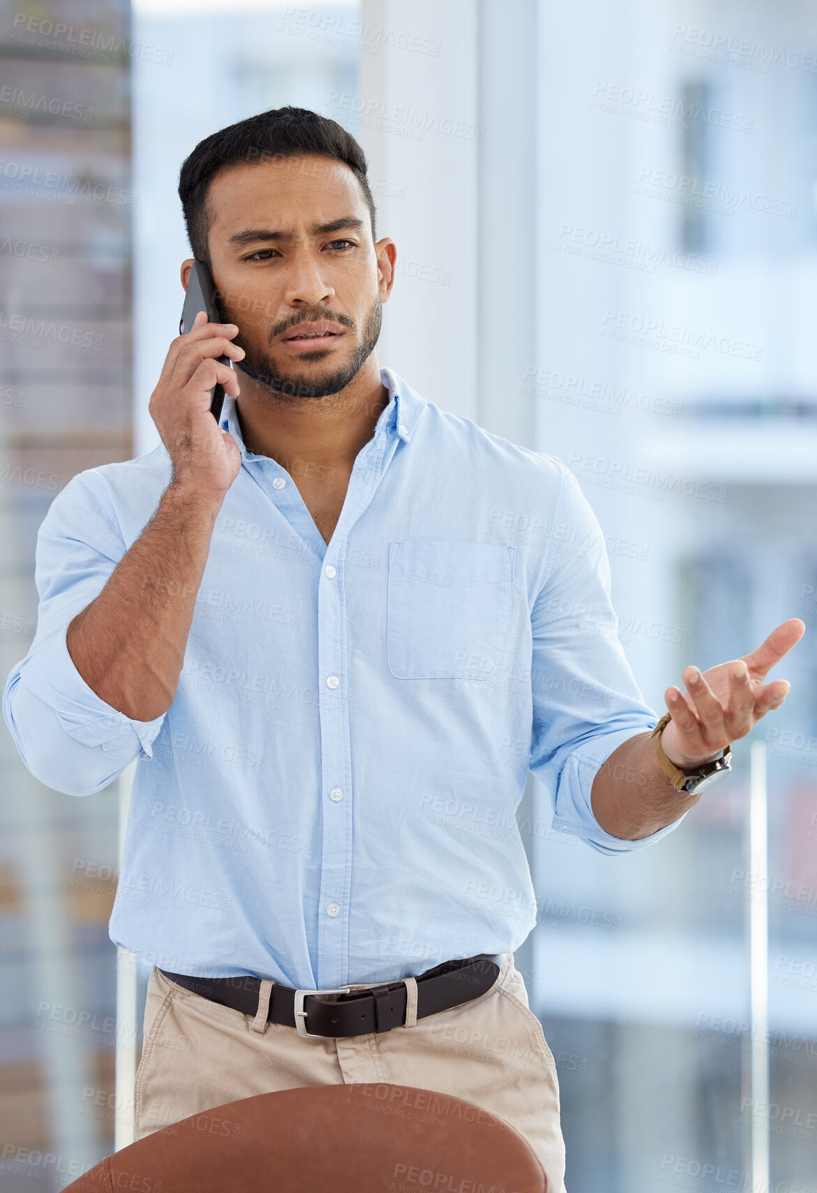 Buy stock photo Shot of a young businessman talking on a cellphone in an office