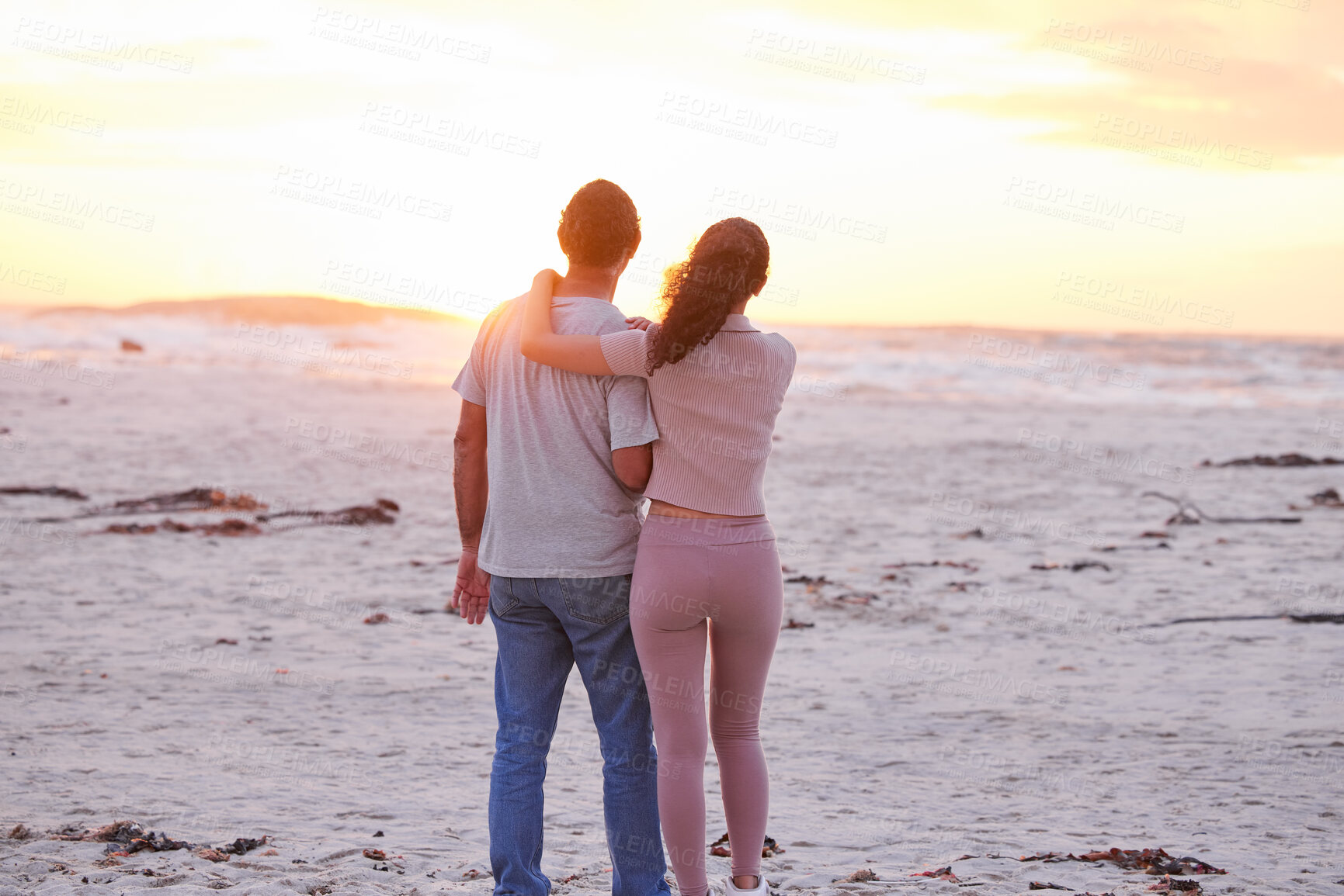 Buy stock photo Sunset, sky and couple on beach with hug, romance and travel holiday together for outdoor adventure. Love, man and woman embrace on evening date with nature, ocean and tropical vacation from back.