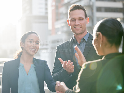 Buy stock photo Shot of two young businesswoman shaking hands against a city background