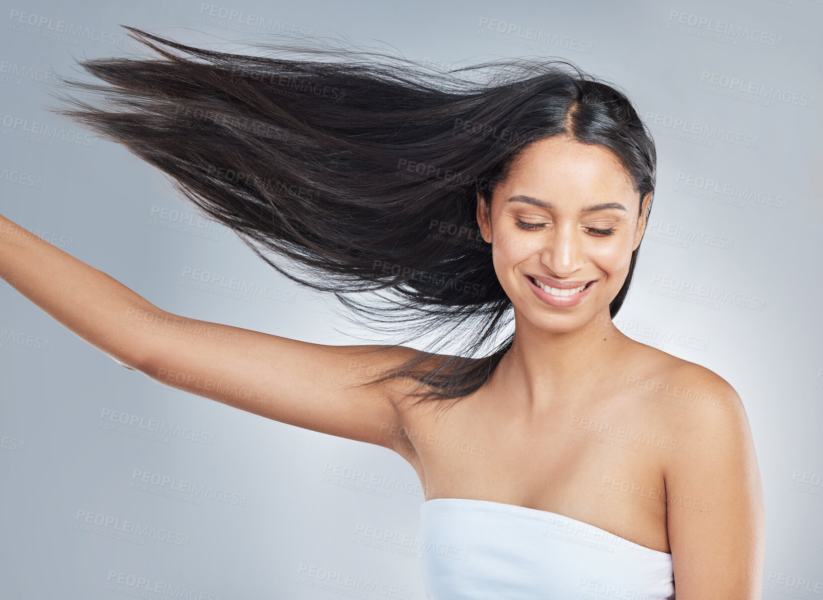 Buy stock photo Shot of an attractive young woman standing alone in the studio and flipping her hair