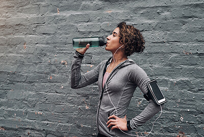 Buy stock photo Shot of a young woman taking a water break while exercising outside