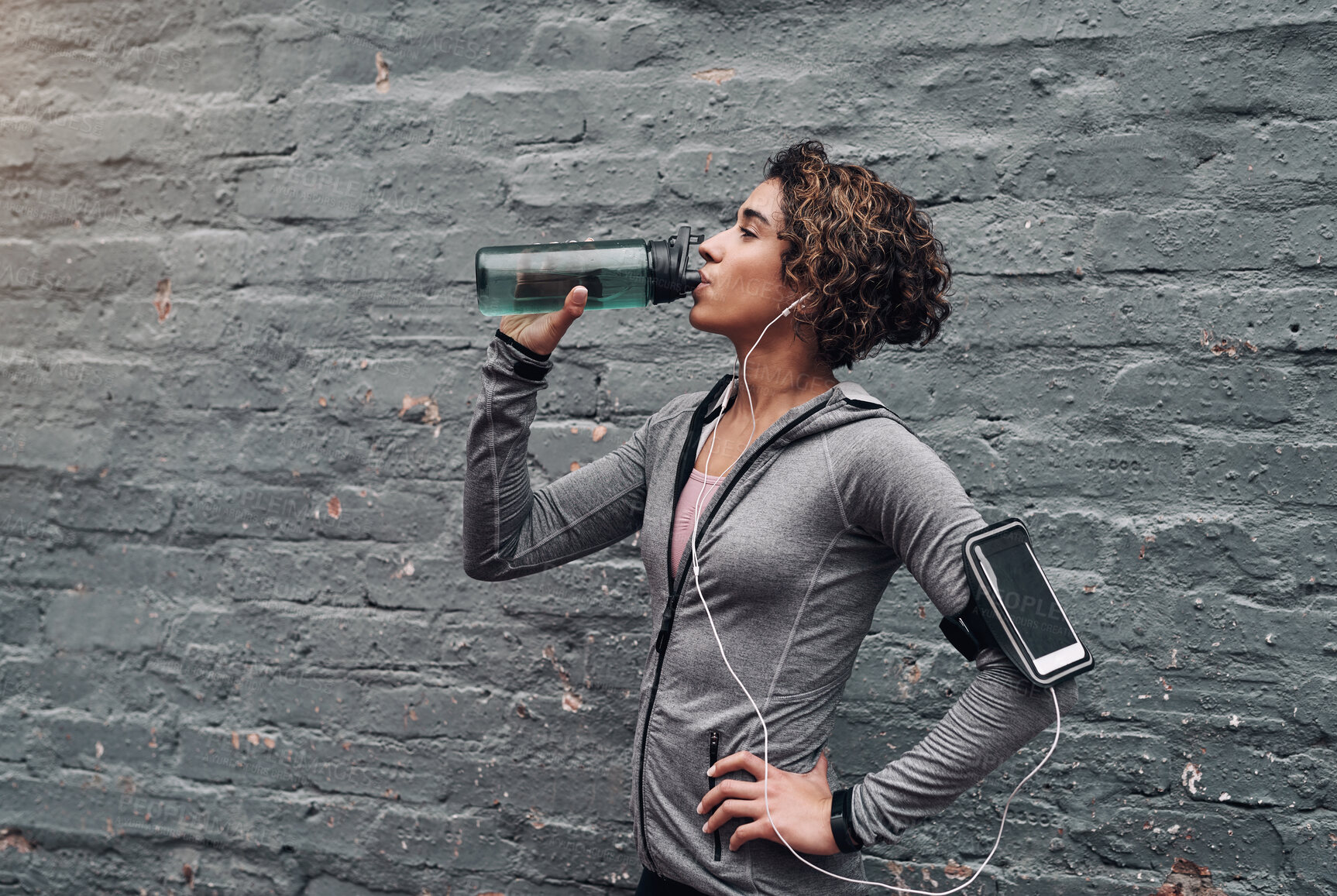 Buy stock photo Shot of a young woman taking a water break while exercising outside