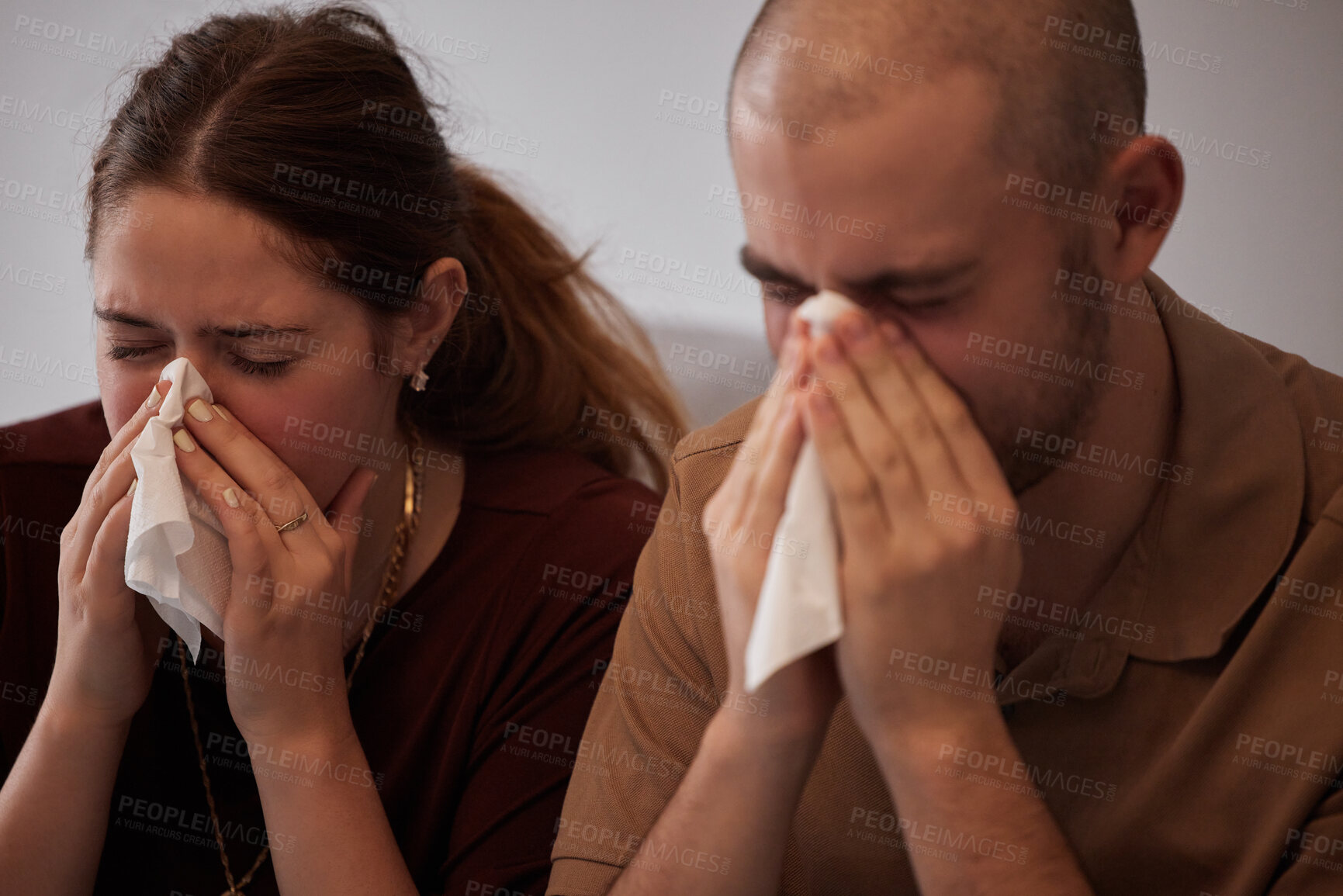 Buy stock photo Shot of a young couple blowing their noses during a cold