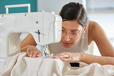 Buy stock photo Shot of a young woman using a sewing machine in her workshop