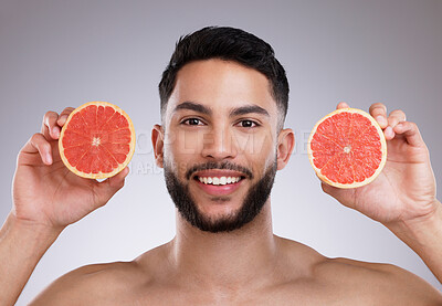 Buy stock photo Studio, portrait and man with grapefruit, skincare and smile for confidence, vitamin c and citrus. Cosmetics, facial health and happy male model with fruit, dermatology or grooming on grey background