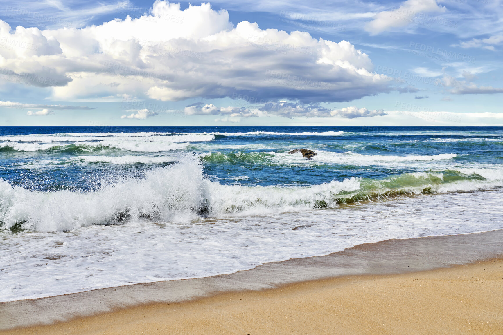 Buy stock photo Waves rolling and crashing the shore at the beach during a summer day outside. Sea, ocean current and tide washing onto the seashore under a cloudy blue sky outdoors in nature