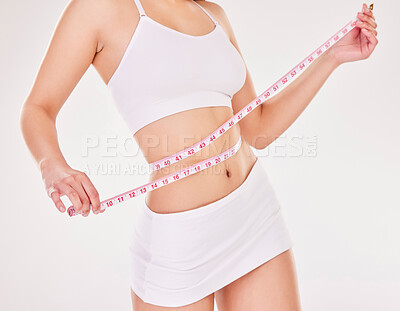 Buy stock photo Studio shot of an unrecognizable young woman using a measuring tape against a grey background