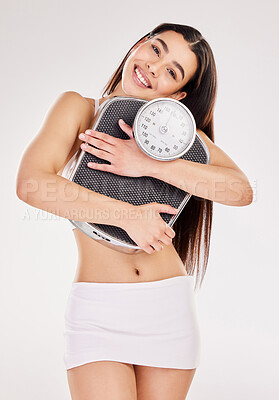Buy stock photo Studio shot of an attractive young woman posing with a weightscale against a grey background