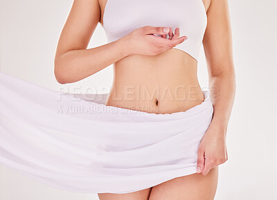 Buy stock photo Studio shot of an unrecognizable young woman posing in her underwear while wrapped in a sheet against a grey background