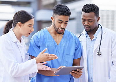 Buy stock photo Shot of a group of doctors using a digital tablet against a city background