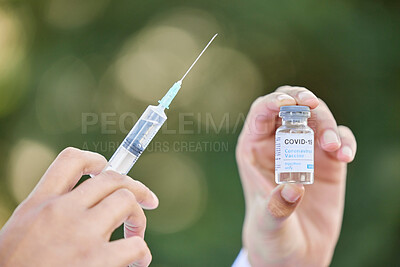 Buy stock photo Shot of an unrecognizale doctor holding a syringe and vial against a city background