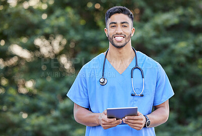 Buy stock photo Shot of a young male doctor using a digital tablet in nature