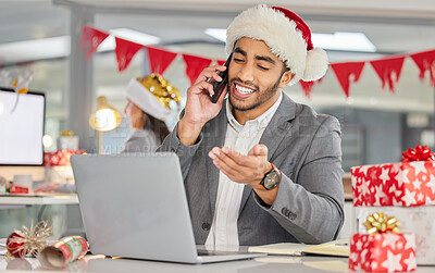 Buy stock photo Shot of a young businessman using a laptop and smartphone in a modern office at Christmas