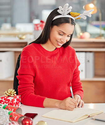 Buy stock photo Shot of a young businesswoman making notes in a modern office at Christmas