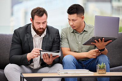 Buy stock photo Shot of two businessmen going through paperwork while using a laptop together in an office