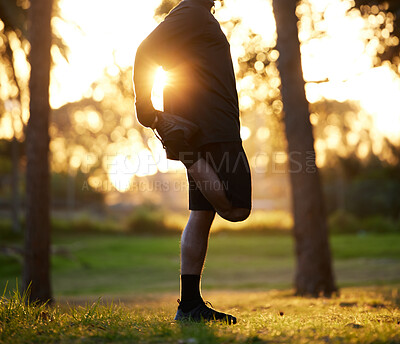 Buy stock photo Shot of a young man stretching his leg before a morning run