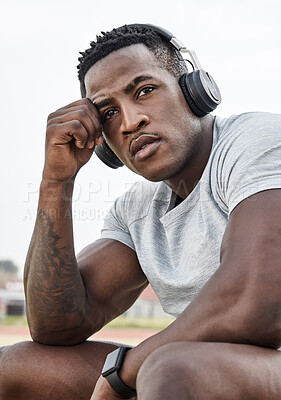 Buy stock photo Shot of a sporty young man wearing his headphones while out for a workout
