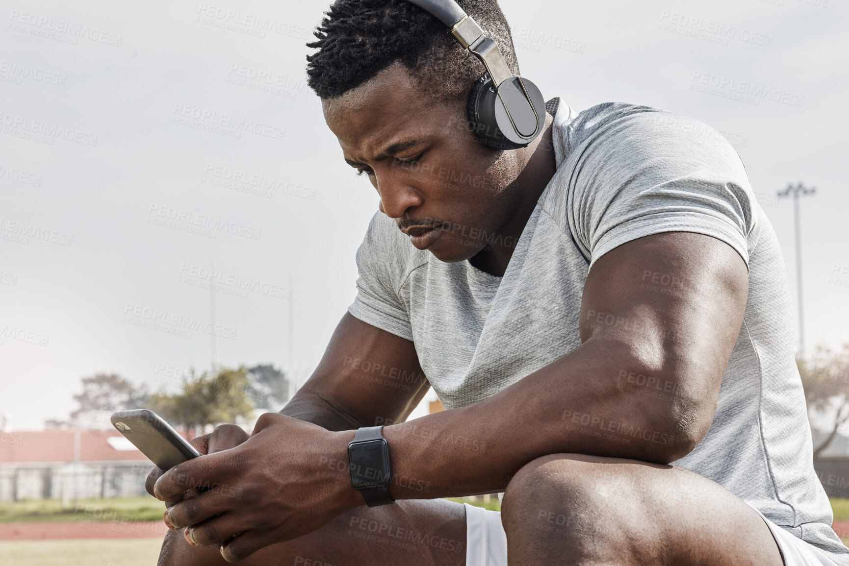 Buy stock photo Shot of a sporty young man wearing his headphones while out for a workout