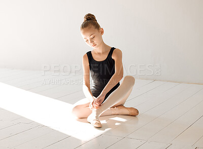 Buy stock photo Shot of a young ballerina tying her ballet slipper in a dance studio