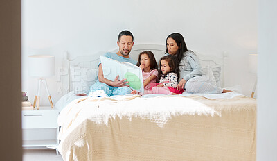 Buy stock photo Shot of a man holding a storybook while sitting with his wife and two daughters