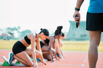 Buy stock photo Rearview shot of an unrecognizable man holding a starting gun while a group of sportswomen take up their positions on track