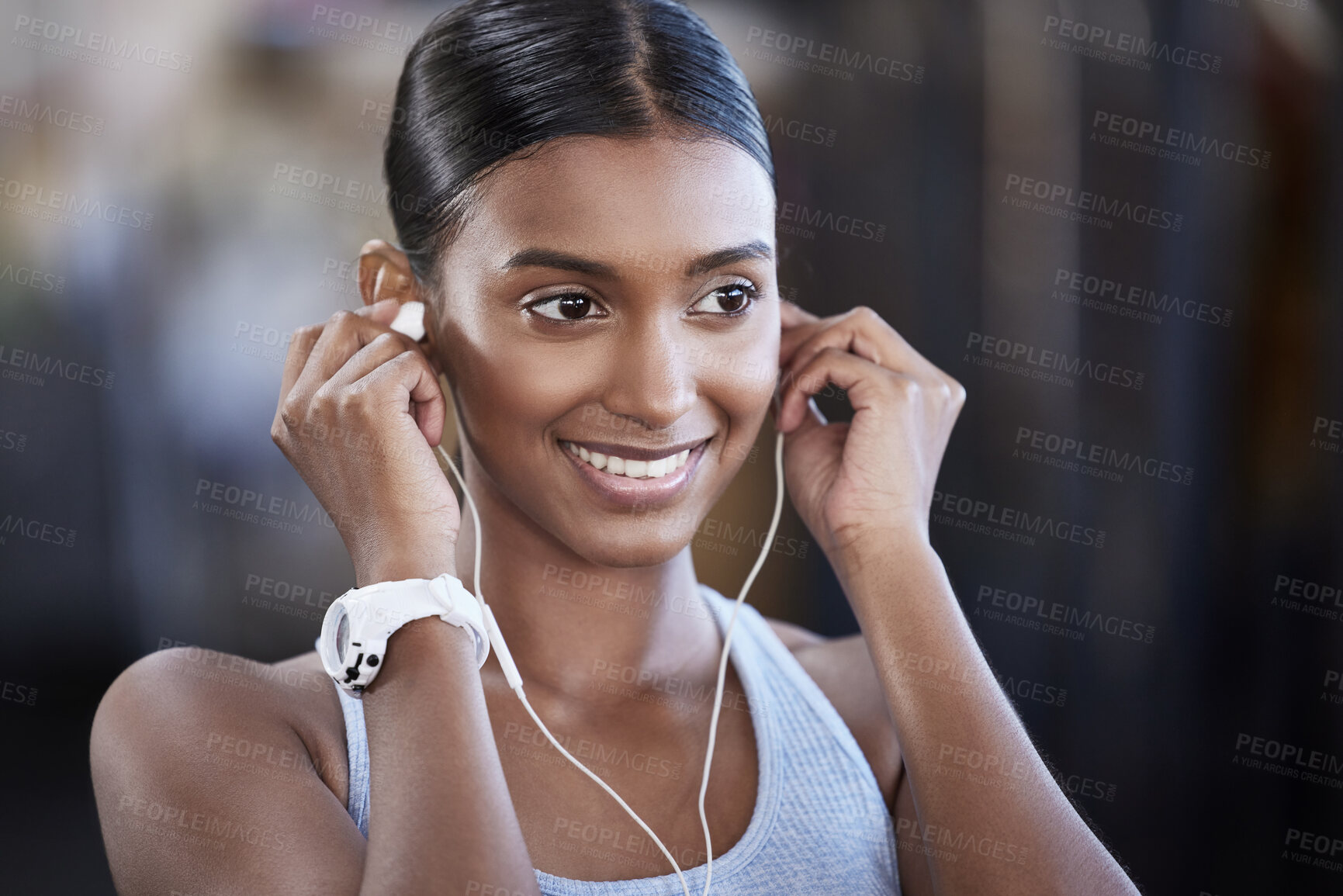 Buy stock photo Shot of a sporty young woman listening to music while exercising in a gym