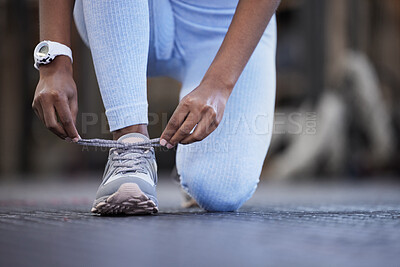 Buy stock photo Closeup shot of an unrecognisable woman tying her laces in a gym